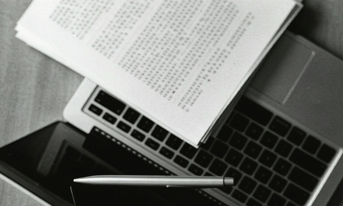 俯视的工作台：笔记本电脑、打印稿和一叠纸
